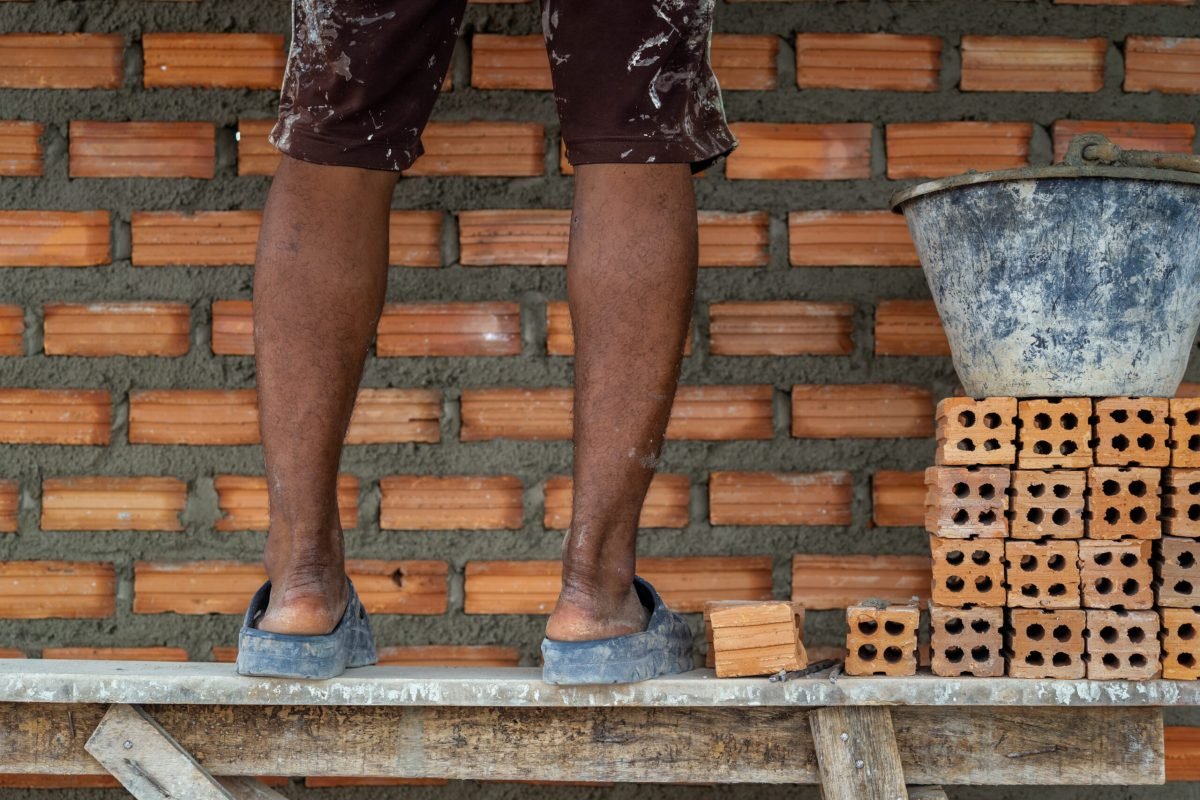 Closeup leg of professional construction worker laying bricks in new industrial site. construct industry and masonry concept